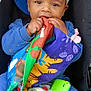 baby, child, car_seat, blue_clothing, cap, toy, baby_bottle, fabric_book, shoes, sitting, cute, infant, play, smiling, hands, face, hooded, casual, indoor, seat
