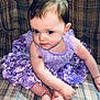 baby, child, dress, lavender, frilly_dress, couch, patterned_fabric, curly_hair, sitting, barefoot, toes, portrait, indoors, cute, young_child, person, skin, face, looking, plush