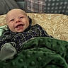 baby, infant, child, smiling, happy, face, portrait, indoor, blanket, green_blanket, plaid_clothing, cushion, couch, seated, lying_down, cozy, home, patterned_background, photography, joy