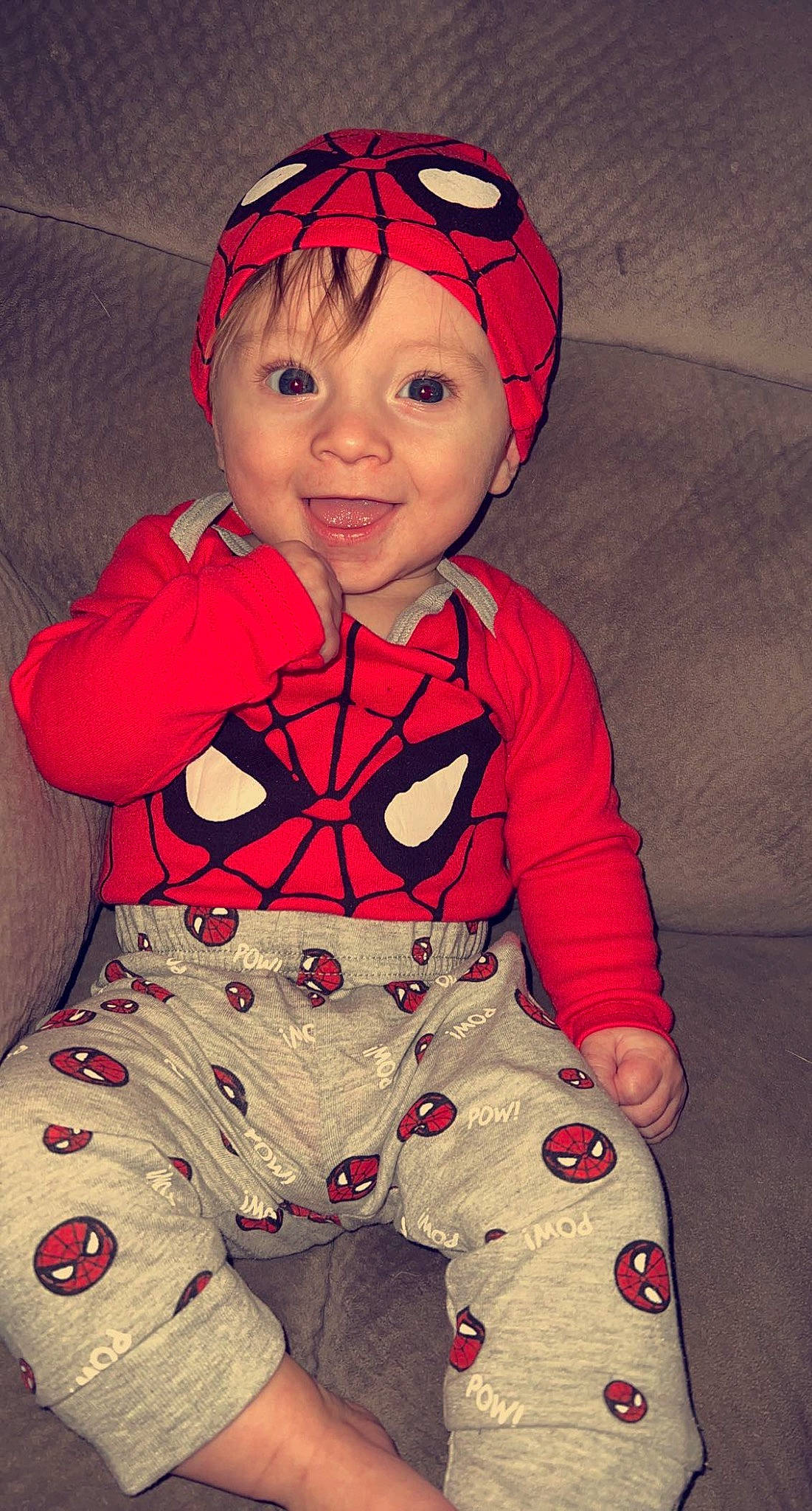 Jameson is registered to the contest to win money with this photo: baby, baby_toddler_clothing, carmine, child, design, face, happy, head, headwear, joy, magenta, orange, pattern, person, personal_protective_equipment, pink, red, sitting, skin, sleeve