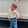 car, child, daylight, denim, fashion, girl, heart_pocket, jeans, long_sleeves, outdoor, portrait, posing, road, shirt, shoes, smiling, standing, toddler, vehicle, white_car