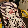 baby, infant, onesie, dalmatian_pattern, striped_baby_seat, smiling, happy, indoor, kitchen, fridge, magnets, toy, yellow_steering_wheel, floor_tiles, blanket, footwear, clothing, person, child, cute