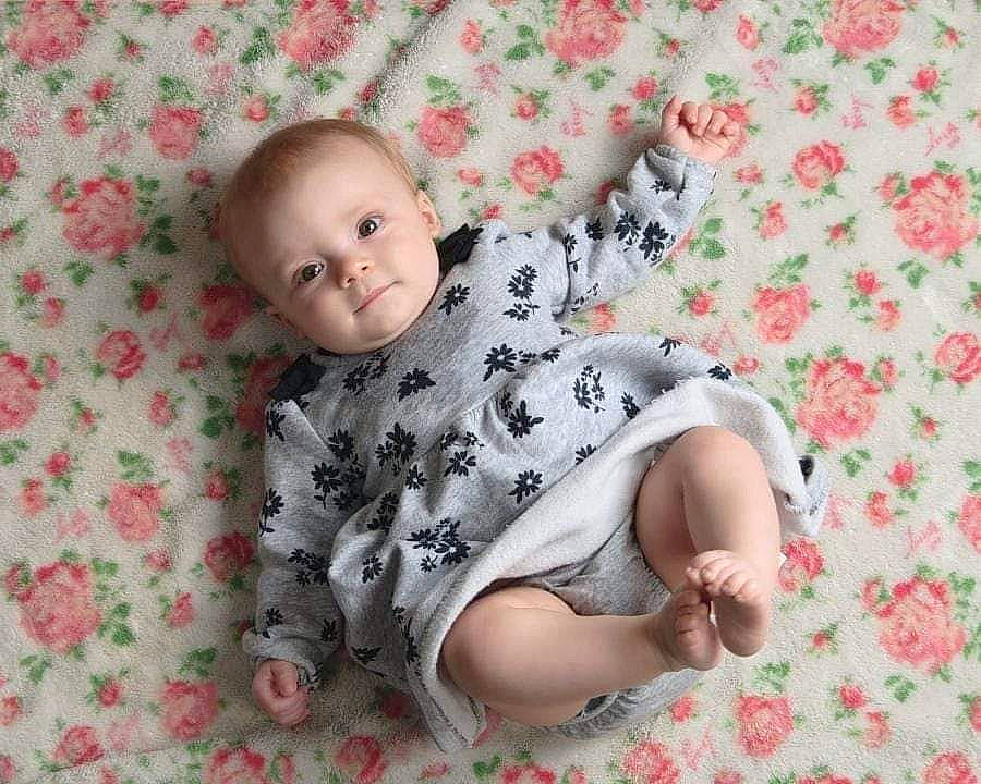 Cassie is registered to the contest to win money with this photo: baby, baby_toddler_clothing, cheek, child, collar, comfort, facial_expression, flooring, grass, linens, pattern, people_in_nature, person, pink, product, sitting, skin, sleeve, t_shirt, toddler