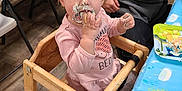 Adaline is registered to the contest to win money with this photo: toddler, child, cake, messy, high_chair, frosting, pink_clothing, table, blue_tablecloth, party, indoor, person, adult, wooden_chair, floor, celebration, food, smearing, cute, hair_tie