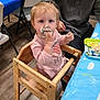 toddler, child, cake, messy, high_chair, frosting, pink_clothing, table, blue_tablecloth, party, indoor, person, adult, wooden_chair, floor, celebration, food, smearing, cute, hair_tie