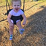 Adaline is registered to the contest to win money with this photo: baby, child, swing, playground, smiling, happy, outdoor, grass, woodchips, fence, trees, clothing, person, feet, socks, sunlight, daytime, fun, joy, kicking