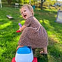 toddler, child, toy_car, smiling, outdoor, grass, greenery, dress, happy, playtime, sunlight, backyard, fun, cute, person, baby, leisure, summer, nature, joyful
