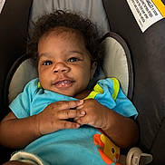 Anfonee is registered to the contest to win money with this photo: baby, infant, child, smiling, blue_onesie, curly_hair, baby_carrier, cushion, warning_label, orange_lion, hands, cute, happy, portrait, indoor, seat, clothing, comfort, closeup, young