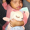 Olivia joined the competition — help win amazing prizes! baby, infant, sleeping, child, plush_toy, bunny, stuffed_animal, pink_clothing, dress, curly_hair, closed_eyes, cuddling, sitting, indoor, portrait, flash_photography, adult_arm, tattoo, blanket, cozy