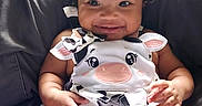 Olivia is registered to the contest to win money with this photo: baby, black_background, chair, child, cow_print, curly_hair, cute, face, fashion, hair_bows, hands, happy, infant, legs, onesie, outdoorless, photography, portrait, seated, smiling