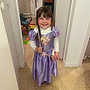 Jade a rejoint le concours — aidez-le/la à gagner de superbes lots ! child, little_girl, smile, purple_dress, princess_costume, braids, indoor, hallway, tile_floor, purse, toy_stroller, play_mat, doorway, radiator, wall_photo, braid, portrait, happy, costume, young_child