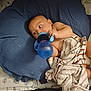 baby, child, blue_cup, cushion, striped_cloth, bed, pillow, indoor, person, infant, bottle, blanket, resting, cute, lying_down, nursery, soft_fabric, comfort, feeding, young