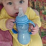 Landen joined the competition — help win amazing prizes! baby, child, yellow_clothing, blue_sippy_cup, hands, face, eyes, indoor, quilt, colorful_background, sitting, infant, closeup, bottle, curious, person, cute, soft_lighting, portrait, young_child
