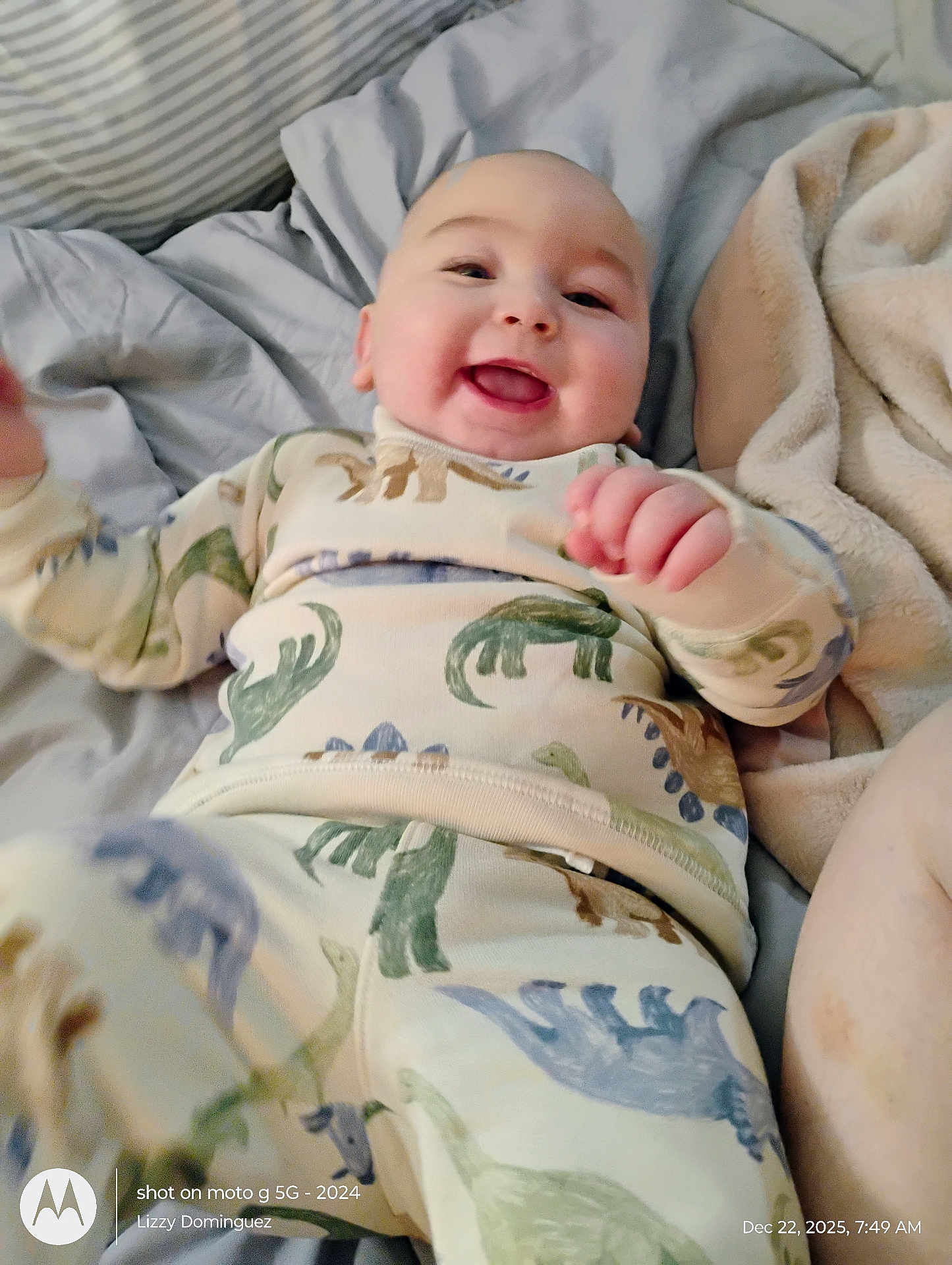 Landen is registered to the contest to win money with this photo: baby, dinosaur_pajamas, smiling, lying_down, bed, blanket, pillow, infant, happy, child, cozy, cute, person, home, sleepwear, soft_fabric, morning, indoors, portrait, playful