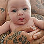 adult, arm, baby, blue_eyes, body_part, child, closeup, cute, expression, fingers, hands, holding, human, infant, person, portrait, skin, tattoos, tongue, wrists