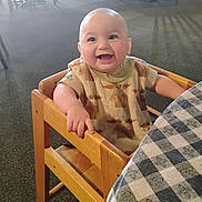 Landen joined the competition — help win amazing prizes! baby, carpet, checkered_tablecloth, child, cute, dining_area, furniture, happy, high_chair, indoor, infant, light, person, portrait, room, seated, shirt, smiling, table, wooden_chair