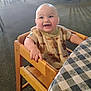 baby, carpet, checkered_tablecloth, child, cute, dining_area, furniture, happy, high_chair, indoor, infant, light, person, portrait, room, seated, shirt, smiling, table, wooden_chair