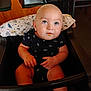 baby, bald_head, blue_eyes, chair, child, curious, cute, face, feeding, food, hands, high_chair, indoor, infant, onesie, restaurant, rocket_ship_pattern, seated, table, wood