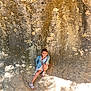 Diane participe au concours pour gagner de l'argent avec cette photo : archaeology, boy, child, cliff, clothing, face, footwear, head, male, nature, outdoors, pants, person, photography, portrait, rock, sandal, shorts, sitting, soil