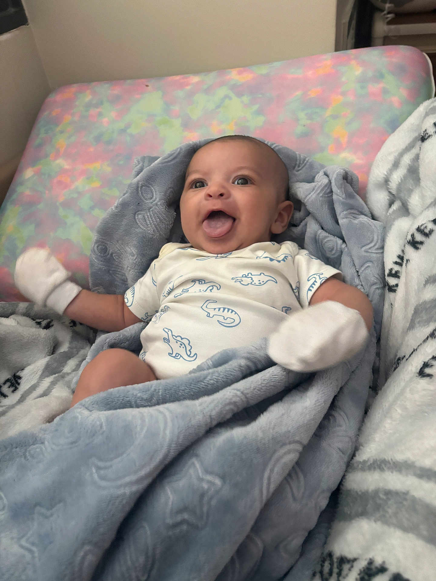 Cylas is registered to the contest to win money with this photo: baby, infant, blanket, bed, mattress, clothing, mittens, face, tongue, smile, happy, cute, child, person, indoors, cozy, plush, pattern, star, pastel
