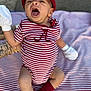 baby, infant, striped_clothing, red_cap, white_mittens, red_socks, blanket, tattooed_arm, yawning, outdoor, person, cute, closeup, expression, sitting, striped_blanket, child, casual_wear, baby_fashion, portrait