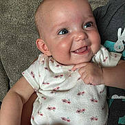 November Rain is registered to the contest to win money with this photo: baby, smiling, infant, onesie, couch, happy, child, person, skin, face, hand, blue_eyes, sitting, indoor, cute, expression, young, plush, comfort, joy