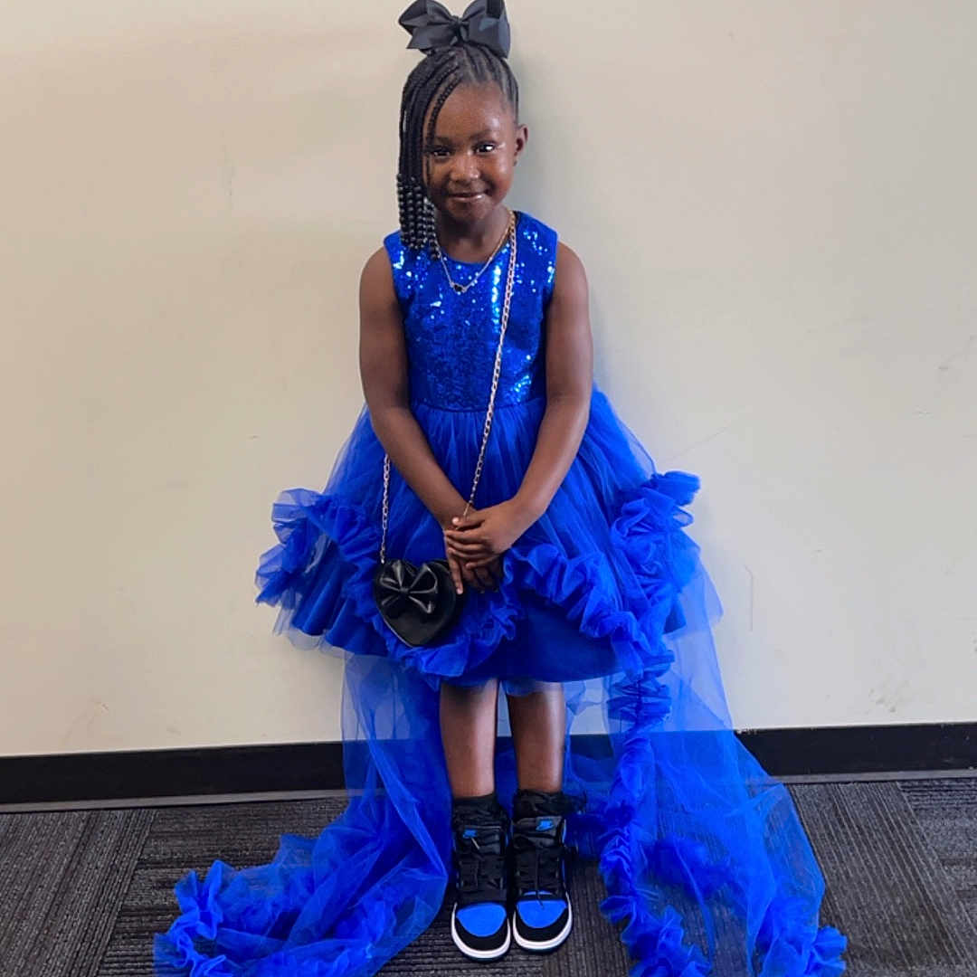 Skylar Davis is registered to the contest to win money with this photo: child, clothing, dress, eveningdress, face, fashion, female, footwear, formalwear, girl, gown, head, highheel, person, photography, portrait, purple, sandal, shoe, sitting