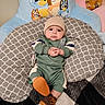 Amaziah is registered to the contest to win money with this photo: baby, child, infant, cushion, beanie, boots, green_outfit, pattern, cartoon, chair, plush_toy, indoor, floor_rug, cute, person, portrait, comfortable, colorful, smiling, cozy