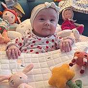 Laïa a rejoint le concours — aidez-le/la à gagner de superbes lots ! baby, child, plush_toys, doll, headband, couch, clothing, footwear, toy, smile, indoor, soft_toy, blanket, cute, infant, face, person, seated, decor, playtime