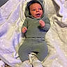Charlie is registered to the contest to win money with this photo: baby, infant, knitwear, hooded_sweater, blanket, soft_toy, cute, child, lying_down, indoors, footwear, expression, cozy, warm_clothing, small_hands, portrait, sleepwear, headwear, smiling, fuzzy_texture