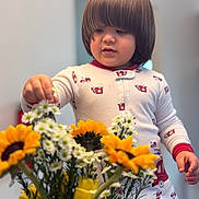 Angel joined the competition — help win amazing prizes! toddler, child, pajamas, flowers, bouquet, sunflowers, tulips, daisies, indoor, cute, curious, person, young_child, hands, face, hair, soft_lighting, cozy, home, nature