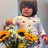 toddler, child, pajamas, flowers, bouquet, sunflowers, tulips, daisies, indoor, cute, curious, person, young_child, hands, face, hair, soft_lighting, cozy, home, nature