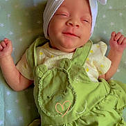 Kaylonni is registered to the contest to win money with this photo: baby, infant, smiling, sleeping, headband, bow, green_dress, bear_design, blanket, star_pattern, cute, peaceful, child, newborn, portrait, soft_lighting, indoors, clothing, happy, lying_down