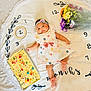 baby, infant, girl, dress, headband, flowers, bouquet, cake, sprinkles, candy, blanket, numbers, embroidery, pink_socks, celebration, milestone, smile, lying_down, cute, indoors