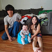 Teegan joined the competition — help win amazing prizes! baby, children, family, siblings, smiling, happy, portrait, indoor, living_room, couch, blankets, pillows, wooden_floor, toy_airplane, blue_seat, long_hair, casual_clothing, sitting, infant, home