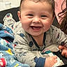 Teegan joined the competition — help win amazing prizes! baby, child, smiling, happy, portrait, face, person, infant, sitting, indoors, blanket, pajamas, clothing, bed, cozy, home, photograph, phone_screen, gallery, family