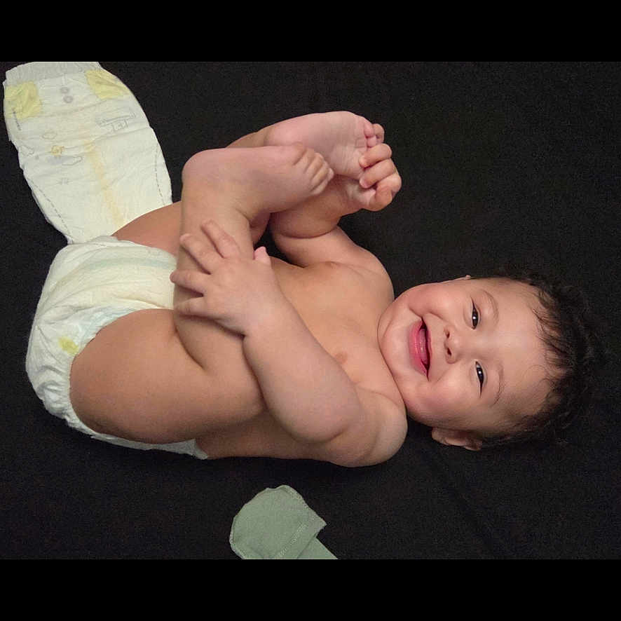 Teegan joined the competition — help win amazing prizes! baby, infant, child, lying_down, smiling, feet, hands, diaper, blanket, indoor, portrait, face, dark_background, candid, happy, playful, self_grabbing, baby_care, wipes, closeup