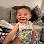 Ezekiah is registered to the contest to win money with this photo: toddler, child, smiling, indoors, couch, blanket, pillow, tank_top, diaper, necklace, happy, cute, young_child, living_room, patterned_pillow, purple_blanket, sitting, playful, casual_clothing, home