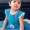 baby, child, girl, blue_dress, headband, crocheted_clothing, bracelets, indoor, carpet, cute, portrait, sitting, young_child, earrings, curious_expression, fashion, accessories, face, person, toddler