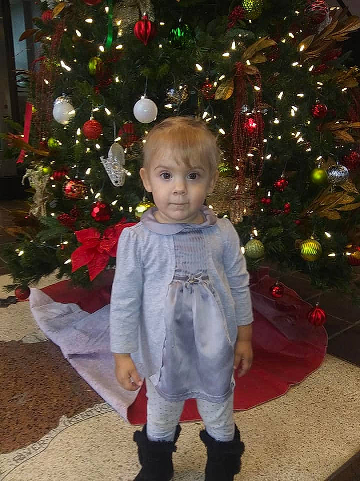 Brylee is registered to the contest to win money with this photo: child, christmas, christmas_decoration, christmas_eve, christmas_ornament, christmas_tree, event, fir, holiday, holiday_ornament, interior_design, outerwear, person, plant, standing, toddler, tree
