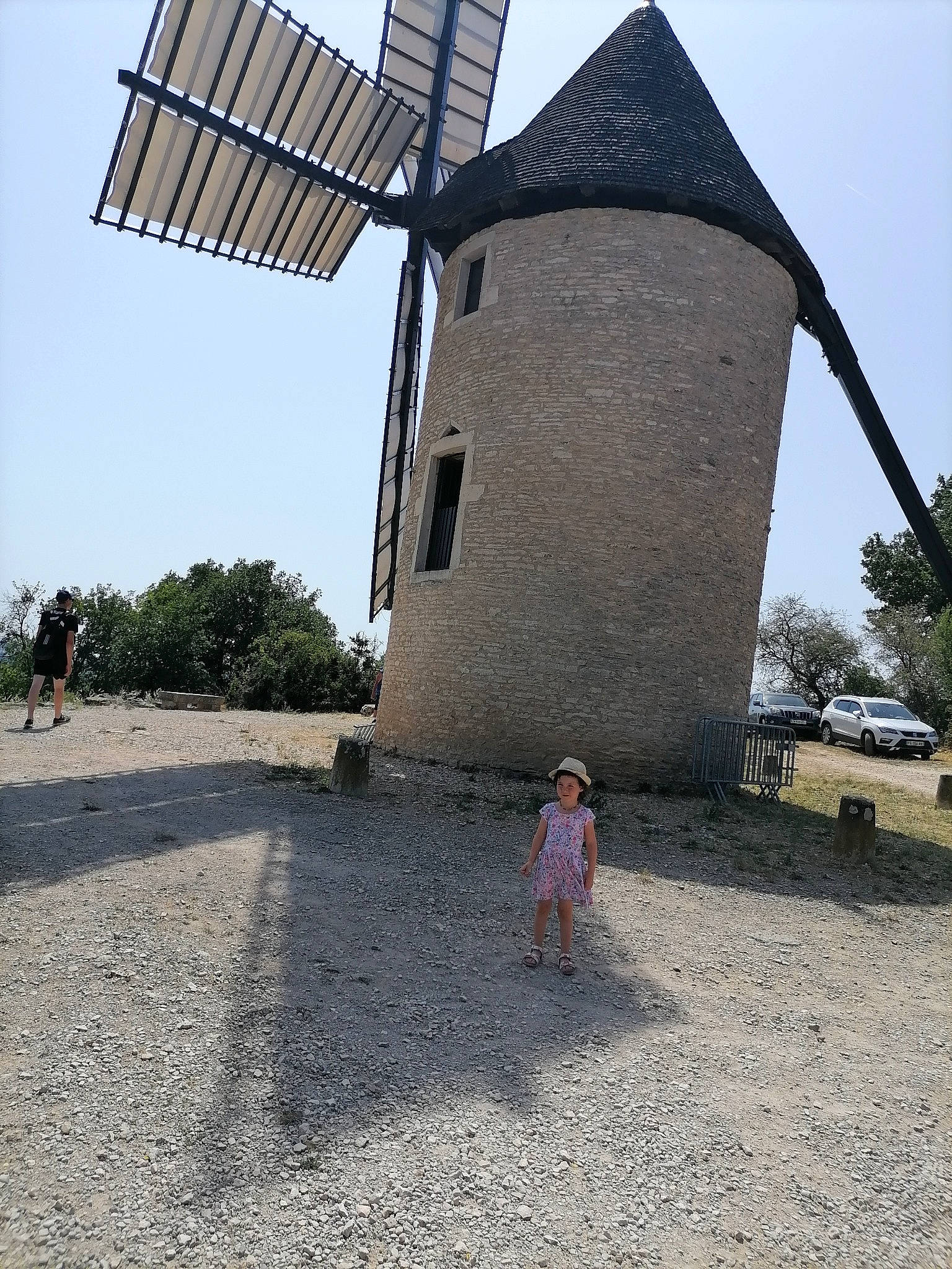 Shanna a rejoint le concours — aidez-le/la à gagner de superbes lots ! automotive_wheel_system, building, grass, landscape, machine, mill, person, plant, pole, public_utility, sky, soil, tire, toddler, travel, tree, wheel, wind, wind_farm, wind_turbine
