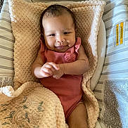Lehlani is registered to the contest to win money with this photo: baby, infant, blanket, baby_seat, smiling, pink_clothing, face, soft_texture, cute, comfortable, indoor, portrait, child, person, closeup, resting, fabric, head, baby_girl, cozy