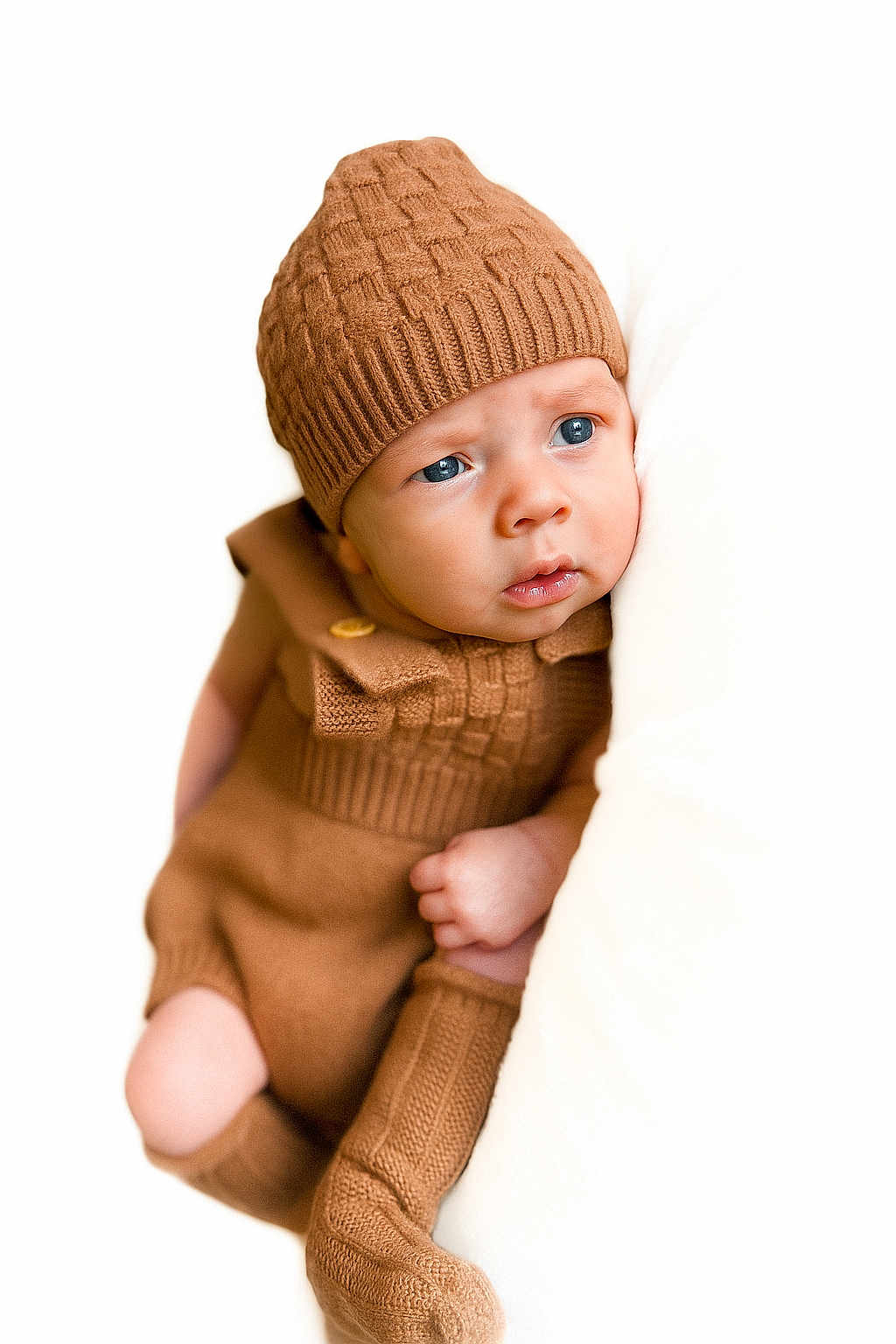 Ryker is registered to the contest to win money with this photo: baby, infant, child, knit_hat, brown_clothing, cozy, cute, portrait, blue_eyes, soft_texture, cushion, warm, indoors, knitwear, sitting, expression, cute_baby, fashion, closeup, person