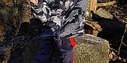 Bryson is registered to the contest to win money with this photo: camouflage_jacket, casual_clothing, child, daylight, forest, ground, happy, leaves, nature, outdoor, pants, person, playful, pose, rock, shoes, smiling, sunlight, trees, young