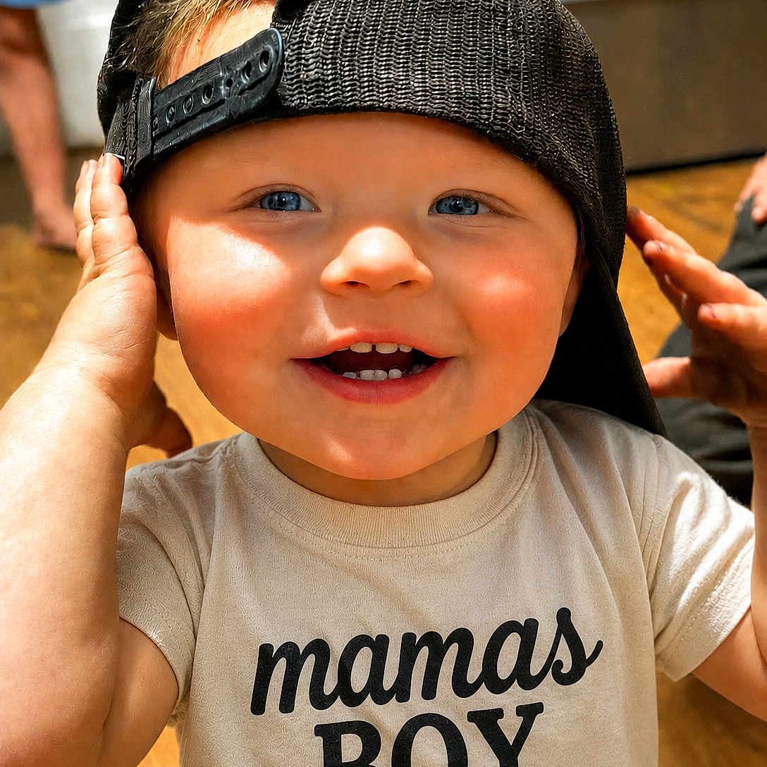 Xander is registered to the contest to win money with this photo: toddler, child, boy, smiling, blue_eyes, cap, backwards_cap, tshirt, mamas_boy, hands, face, indoor, wooden_floor, happy, cute, baby, portrait, casual, playful, closeup