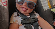 Xander is registered to the contest to win money with this photo: baby, car_seat, casual, child, cute, happy, indoor, infant, monkey_print, onesie, person, playful, safety, seat, seatbelt, smiling, sunglasses, toddler, tongue_out, toy