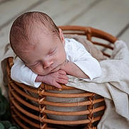 Siméo participe au concours pour gagner de l'argent avec cette photo : newborn, baby, sleeping, basket, blanket, wood_floor, infant, peaceful, resting, cozy, soft_texture, hands, head, white_clothing, indoor, portrait, closeup, natural_light, cute, serene