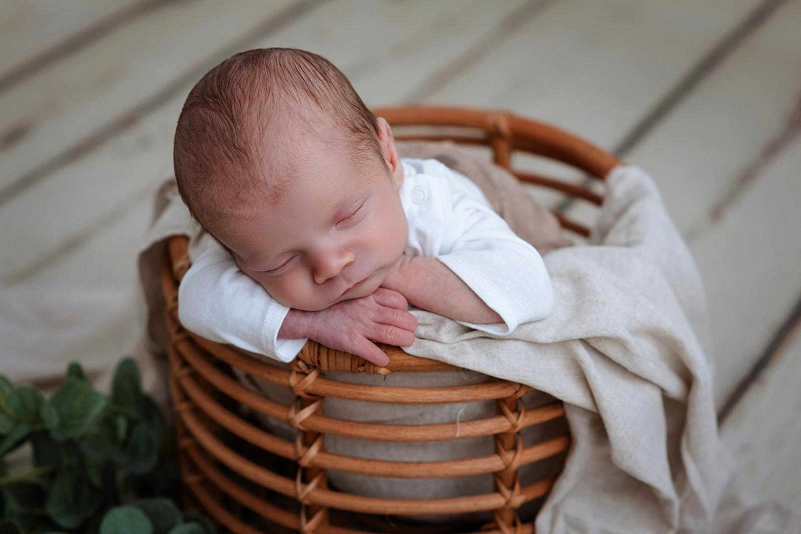 Siméo participe au concours pour gagner de l'argent avec cette photo : newborn, baby, sleeping, basket, blanket, wood_floor, infant, peaceful, resting, cozy, soft_texture, hands, head, white_clothing, indoor, portrait, closeup, natural_light, cute, serene