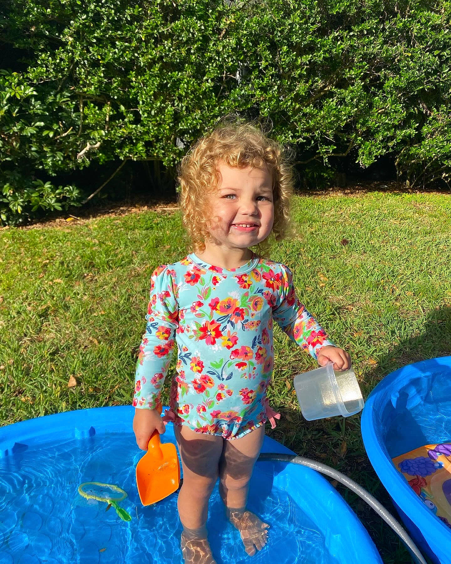 Norah is registered to the contest to win money with this photo: baby_toddler_clothing, child, electric_blue, fun, garden, grass, happy, joy, lawn, leisure, pattern, people_in_nature, person, plant, play, recreation, shrub, sitting, smile, summer