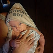 Wyatt joined the competition — help win amazing prizes! baby, towel, hood, mamas_boy, infant, hand, person, holding, skin, arm, indoor, wooden_wall, soft_lighting, curious, cozy, snug, portrait, closeup, child, warm